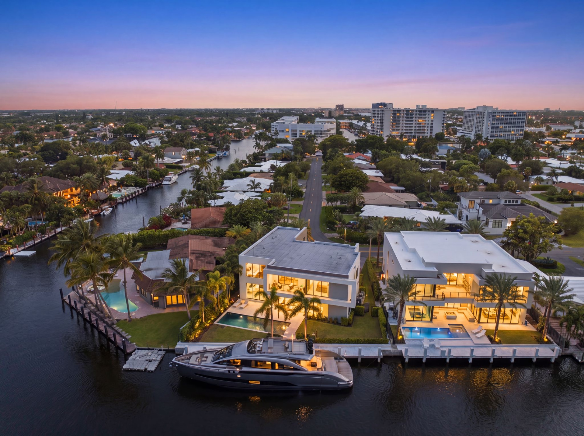 Casa Aqua illuminated at twilight with a yacht at the private dock
